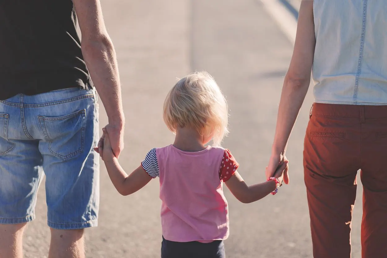 a child holding hands with a man and woman