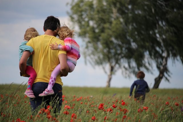 a man carrying children in a field of flowers
