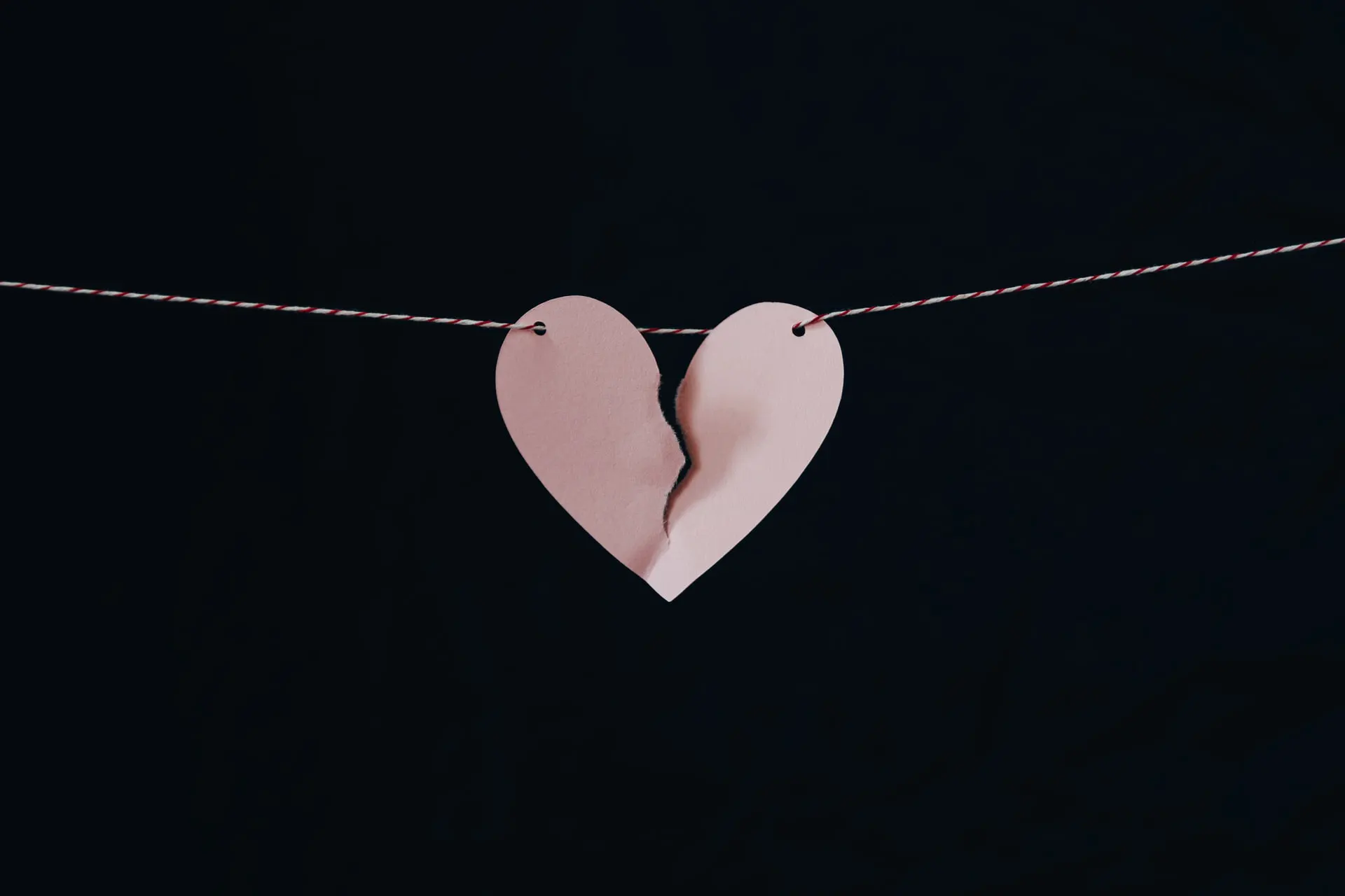 a paper heart with a broken piece of paper on a string